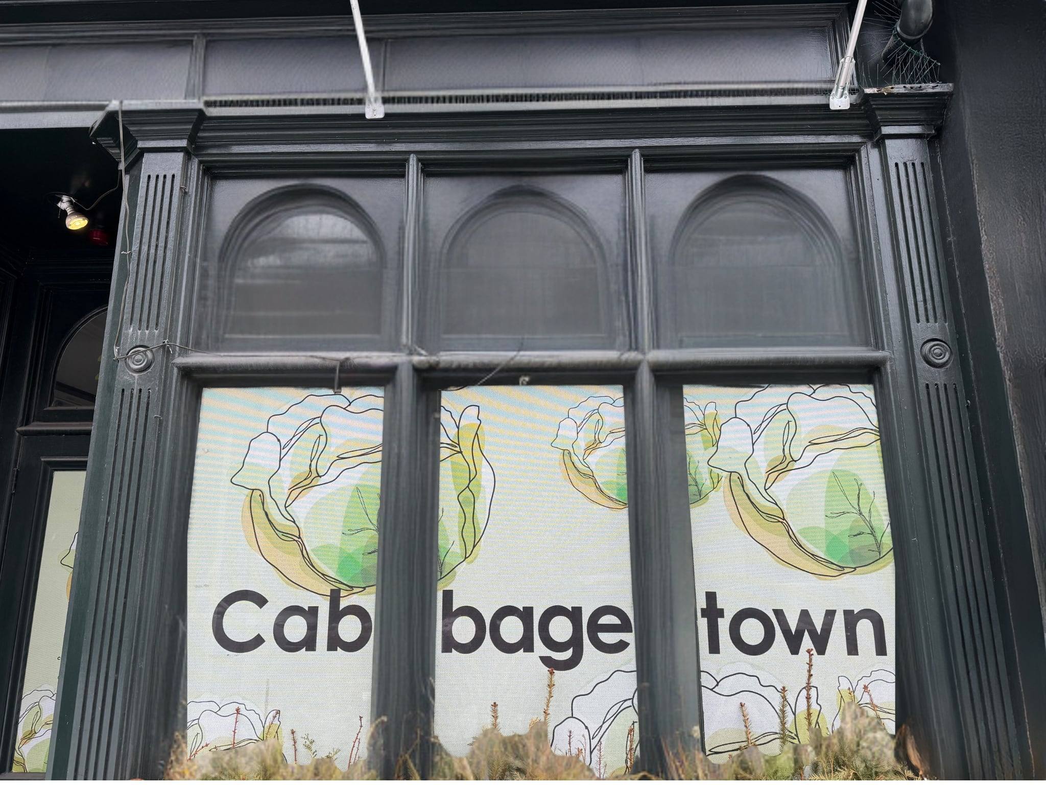 A dark green storefront with cabbage illustrations and the word Cabbagetown across the windows.