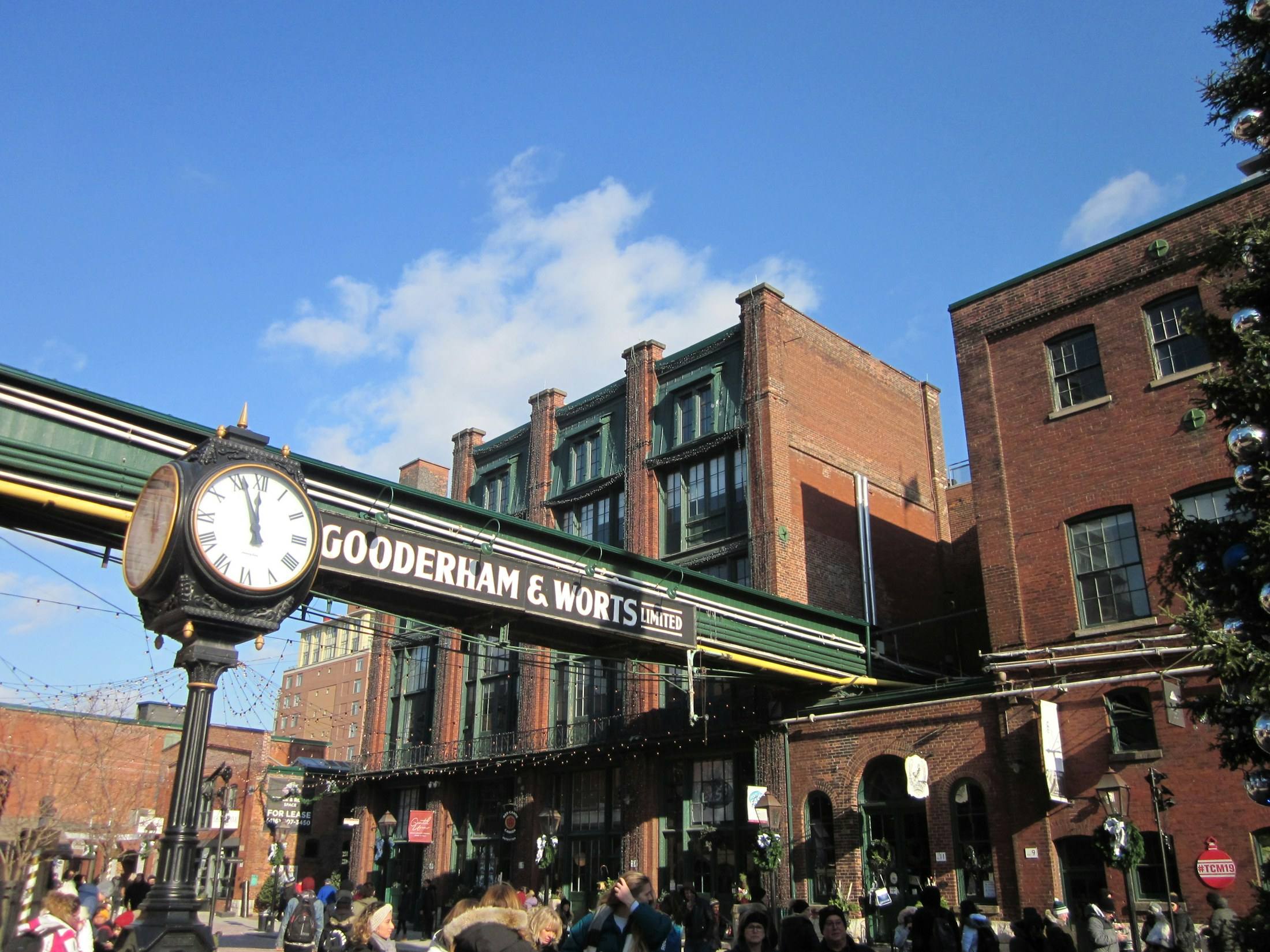 The Gooderham and Worts clock and red-brick buildings in the Distillery District under a blue sky.