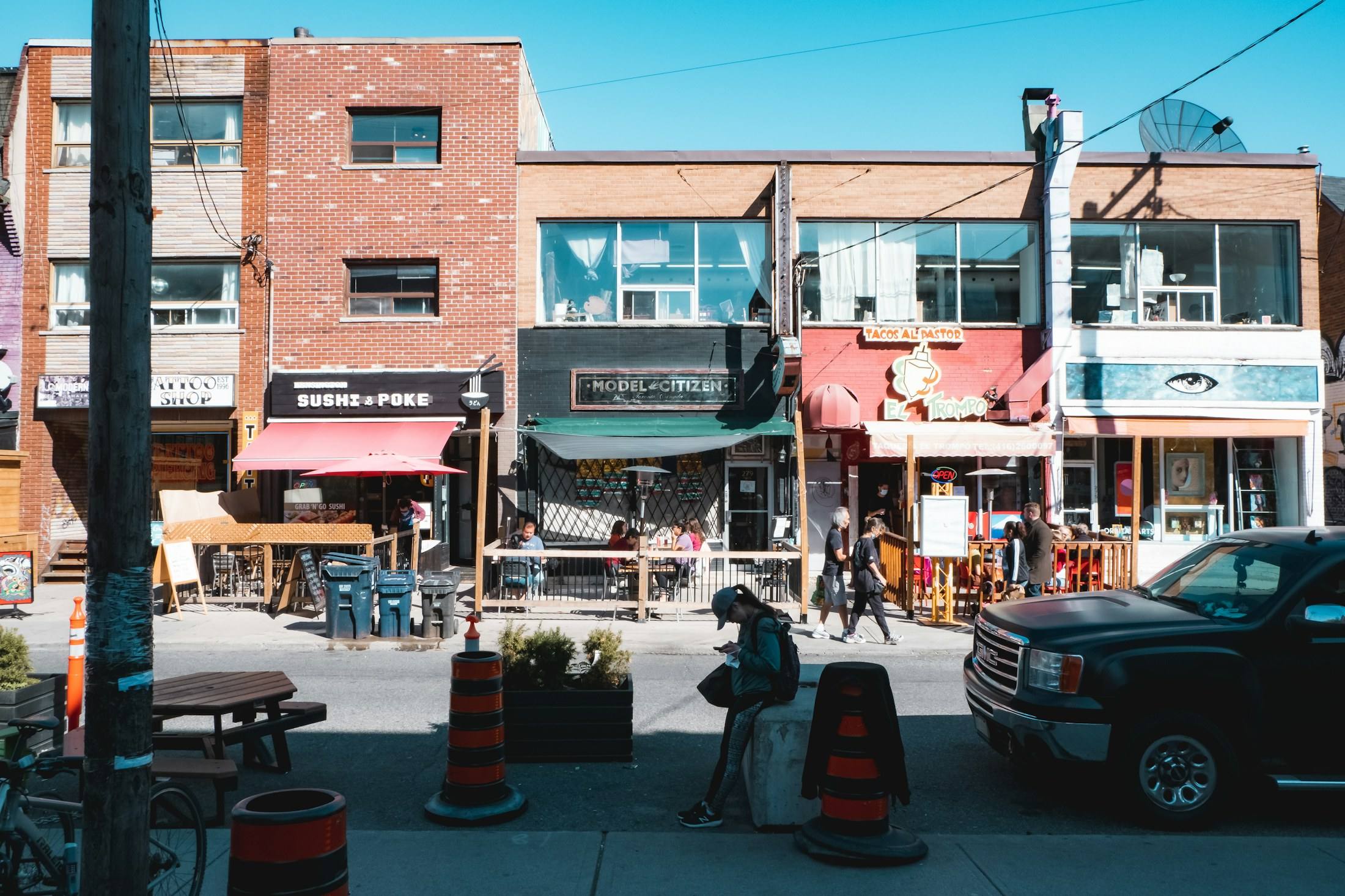 Colourful independent shops and patios on a sunny street in Kensington Market.