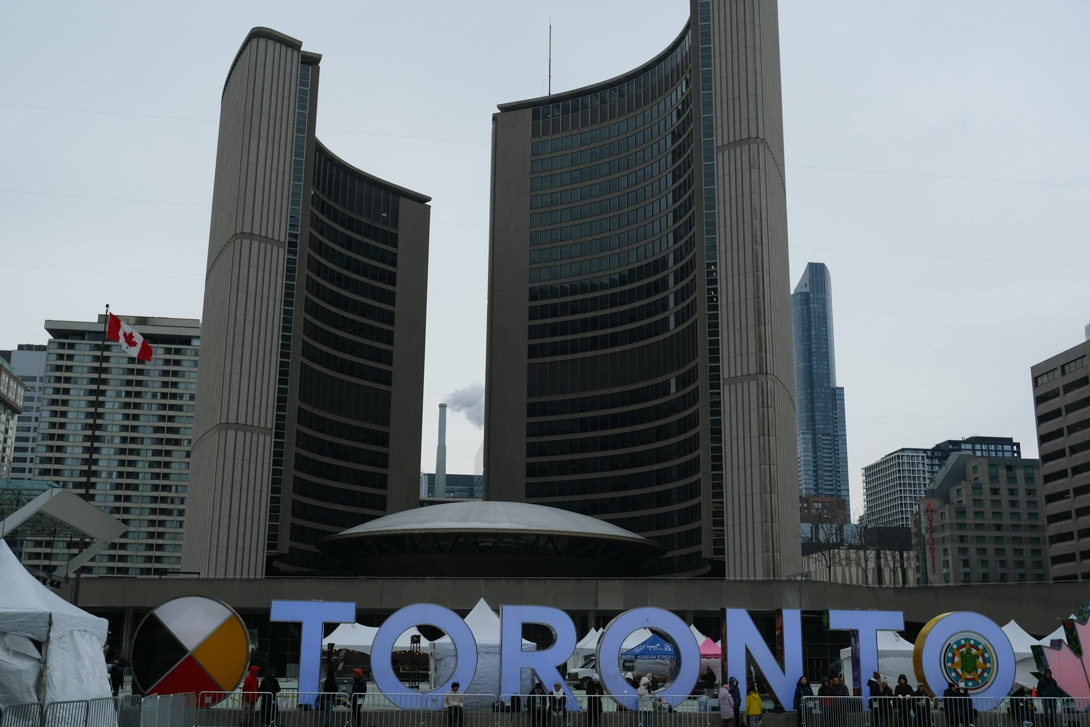 The TORONTO sign at Nathan Phillips Square, with City Hall's two curved towers behind it.